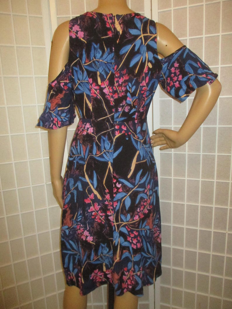 May include: A black floral print dress with cold shoulder straps and short ruffle sleeves. The dress has a fitted bodice and a flowy skirt.