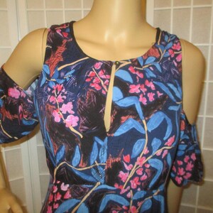May include: A blue, pink, and white floral print cold shoulder dress with a V-neckline and ruffled sleeves.