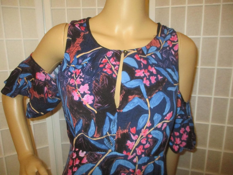 May include: A blue, pink, and white floral print cold shoulder dress with a V-neckline and ruffled sleeves.