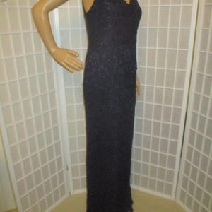 May include: A long, dark blue lace dress with a V-neckline and sleeveless design.