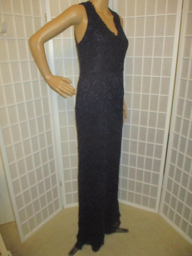 May include: A long, dark blue lace dress with a V-neckline and sleeveless design.