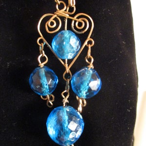 May include: A blue glass bead necklace with a gold wire heart pendant and dangling blue glass beads.