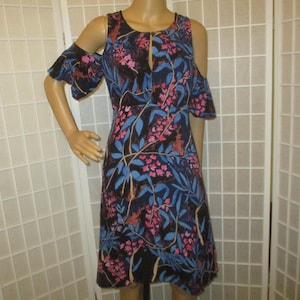 May include: A black dress with a floral print featuring pink and blue flowers. The dress has a cold shoulder design and a keyhole neckline.