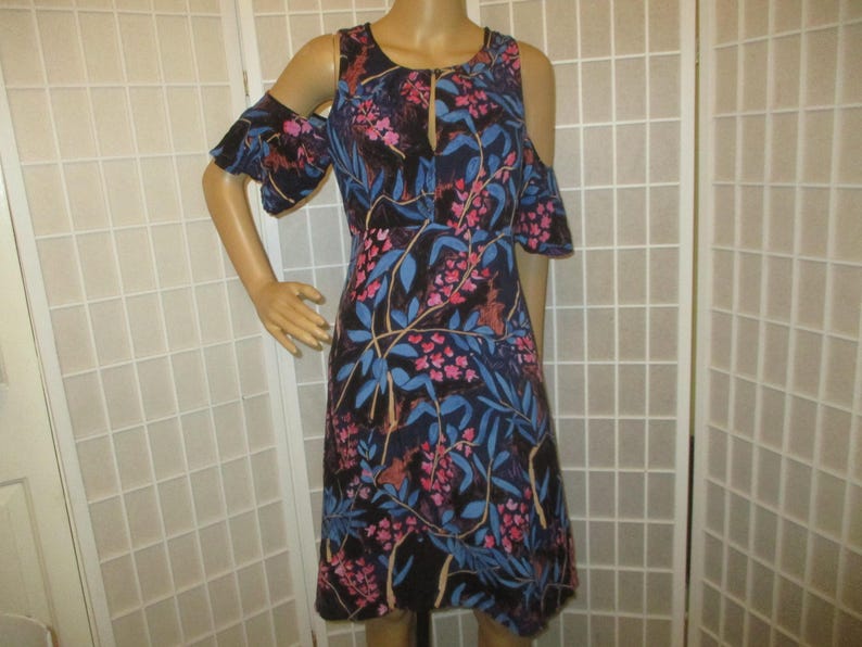 May include: A black dress with a floral print featuring pink and blue flowers. The dress has a cold shoulder design and a keyhole neckline.