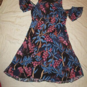May include: A black floral dress with a cold shoulder design and ruffled sleeves. The dress has a blue and pink floral print on a black background.