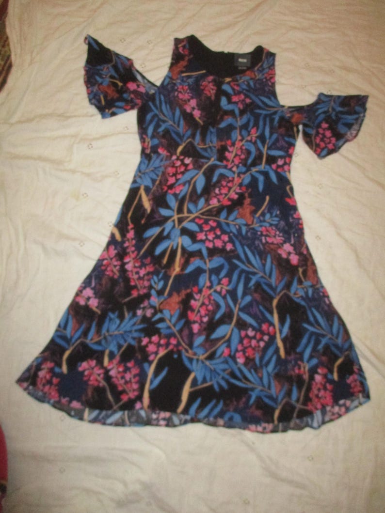 May include: A black floral dress with a cold shoulder design and ruffled sleeves. The dress has a blue and pink floral print on a black background.