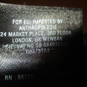 May include: Black and white label with the text "FOR EU: IMPORTED BY ANTHROPOLOGIE 24 MARKET PLACE 3RD FLOOR LONDON, UK WIW8AN CIF VAT NO GB-684936382 08575104 RN: 66170 CA 32054"