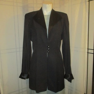May include: A black blazer with a satin collar and cuffs. The blazer has a fitted silhouette and a single-breasted closure with three buttons.