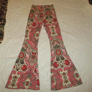 Puede incluir: Pantalones acampanados con estampado de cachemira en tonos rosa, rojo y verde. Los pantalones tienen un dise&ntilde;o repetitivo y una pernera ancha. Est&aacute;n hechos de un material suave y tienen cintura el&aacute;stica. Los pantalones est&aacute;n planos.