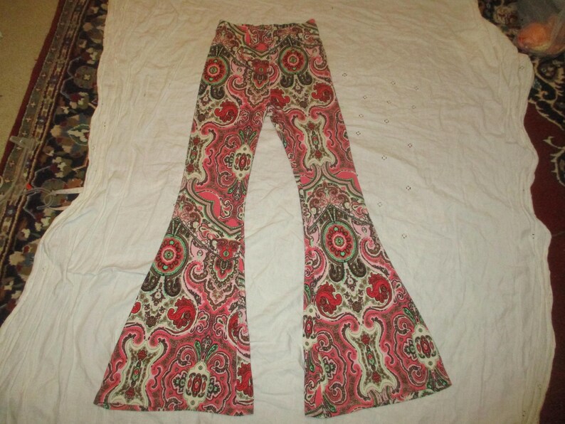 Puede incluir: Pantalones acampanados con estampado de cachemira en tonos rosa, rojo y verde. Los pantalones tienen un dise&ntilde;o repetitivo y una pernera ancha. Est&aacute;n hechos de un material suave y tienen cintura el&aacute;stica. Los pantalones est&aacute;n planos.