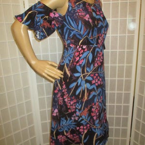 May include: A black floral print dress with cold shoulder straps and ruffled sleeves. The dress has a fitted bodice and a flowing skirt.
