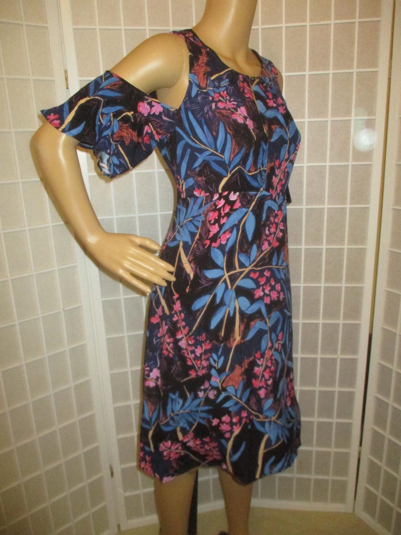 May include: A black floral print dress with cold shoulder straps and ruffled sleeves. The dress has a fitted bodice and a flowing skirt.