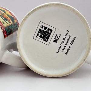 Puede incluir: Dos tazas de cer&aacute;mica blanca con asas, una con una ilustraci&oacute;n colorida y la otra con un logotipo y texto. La base de una taza muestra el texto "Made in Taiwan". Las tazas est&aacute;n sobre una superficie blanca.
