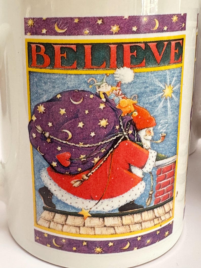 Puede incluir: Taza de cer&aacute;mica blanca con una ilustraci&oacute;n festiva. El dise&ntilde;o presenta a Pap&aacute; Noel en un tejado, llevando un saco de regalos, con la palabra &laquo;BELIEVE&raquo; encima. El borde tiene estrellas y lunas crecientes.