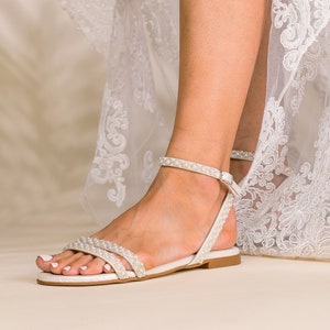 K&ouml;nnte beinhalten: Wei&szlig;e Braut-Sandalen mit Perlenbesatz und Kn&ouml;chelriemen.