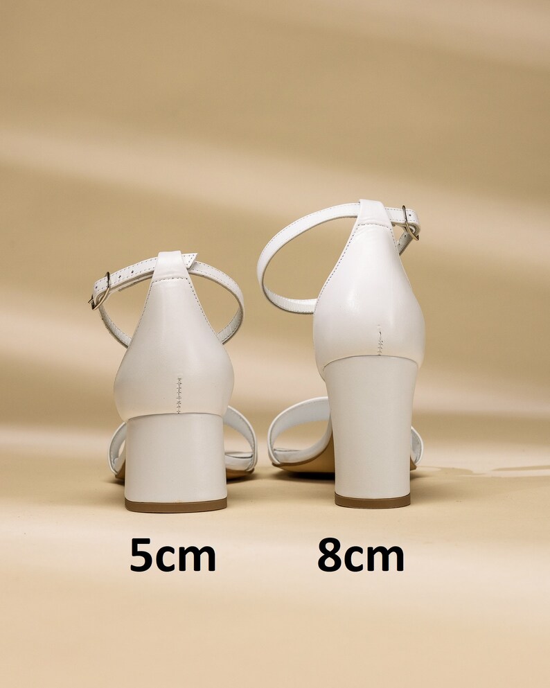 Puede incluir: Dos pares de sandalias de tac&oacute;n de cuero blanco con tiras de tobillo. Las sandalias de la izquierda tienen un tac&oacute;n de 5 cm y las sandalias de la derecha tienen un tac&oacute;n de 8 cm.