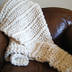 May include: A white crocheted throw blanket draped over a brown leather armchair.