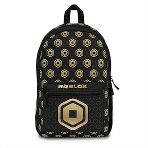 May include: Black backpack with a gold geometric pattern and the Roblox logo. The backpack features a front zippered pocket with the Roblox logo and a large gold emblem. The bag has a top handle and black zippers.