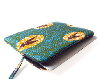 May include: A rectangular laptop sleeve with a colorful African wax print. The fabric features a pattern of blue, green, and yellow ovals with a bird-like design. A black zipper and pull complete the design.