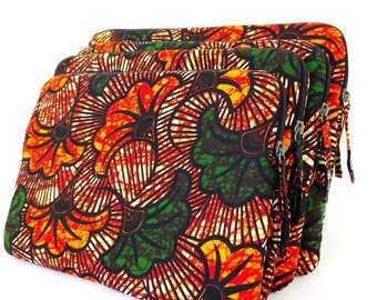 May include: A set of three rectangular zippered pouches featuring a vibrant repeating pattern of stylized orange, yellow, and green floral shapes on a black background. Each pouch has a silver-toned metal zipper closure with a matching fabric pull tab.