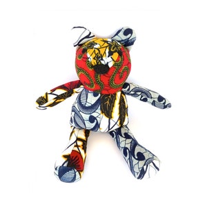 May include: A colorful patchwork teddy bear with a blue, red, yellow, and white patterned fabric. The bear is sitting with its legs outstretched.