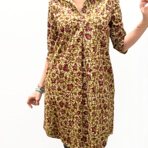 May include: A long-sleeved shirt dress with a collared neckline and a floral print in shades of green, brown, and white.