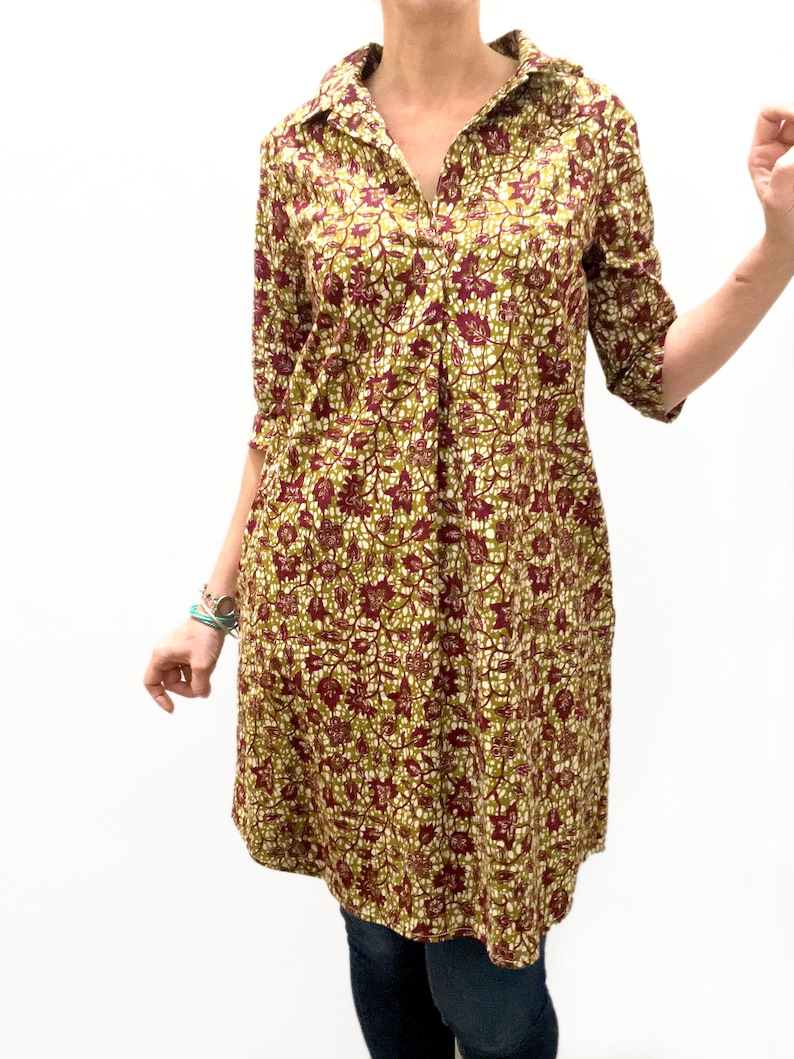 May include: A long-sleeved shirt dress with a collared neckline and a floral print in shades of green, brown, and white.