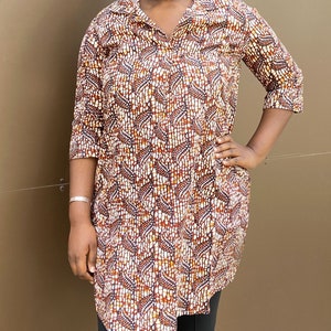May include: A long-sleeved shirt with a brown, white, and orange geometric pattern. The shirt has a collar and a button-up front.