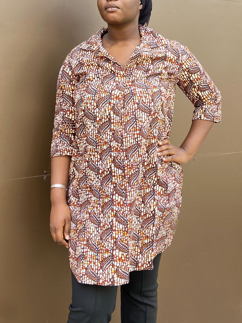 May include: A long-sleeved shirt with a brown, white, and orange geometric pattern. The shirt has a collar and a button-up front.
