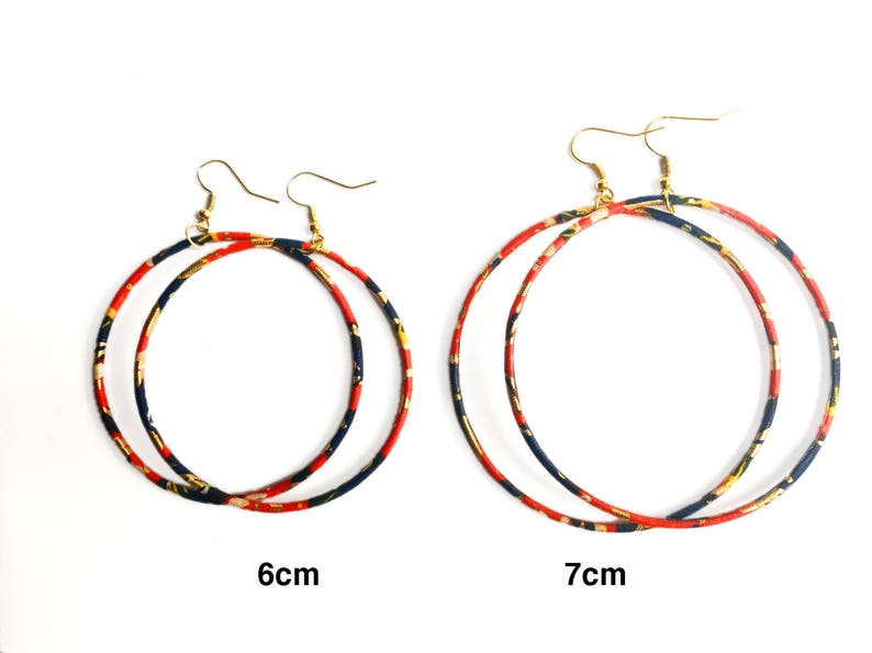May include: Two pairs of hoop earrings. The earrings have a gold-colored hook and a circular hoop design. The hoops are decorated with a pattern of red, navy, and gold. One pair is 6 cm in diameter, and the other is 7 cm.