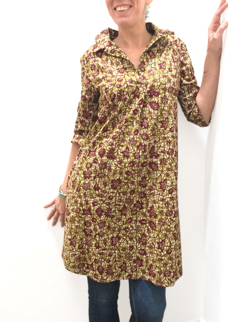 May include: A long-sleeved collared dress with a floral print in shades of green, brown, and white. The dress has a button-up front and a relaxed fit.