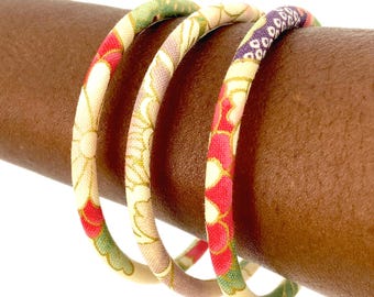 Pulseras japonesas chapadas en oro, de tamaño pequeño o grande, joyería de tela con flores japonesas sobre fondo crudo.