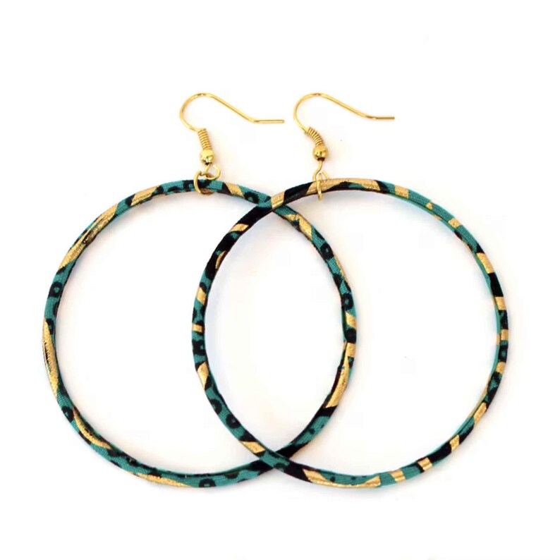 May include: A pair of large hoop earrings with gold-colored hooks. The hoops are decorated with a teal, black, and gold pattern. The earrings are displayed against a white background.