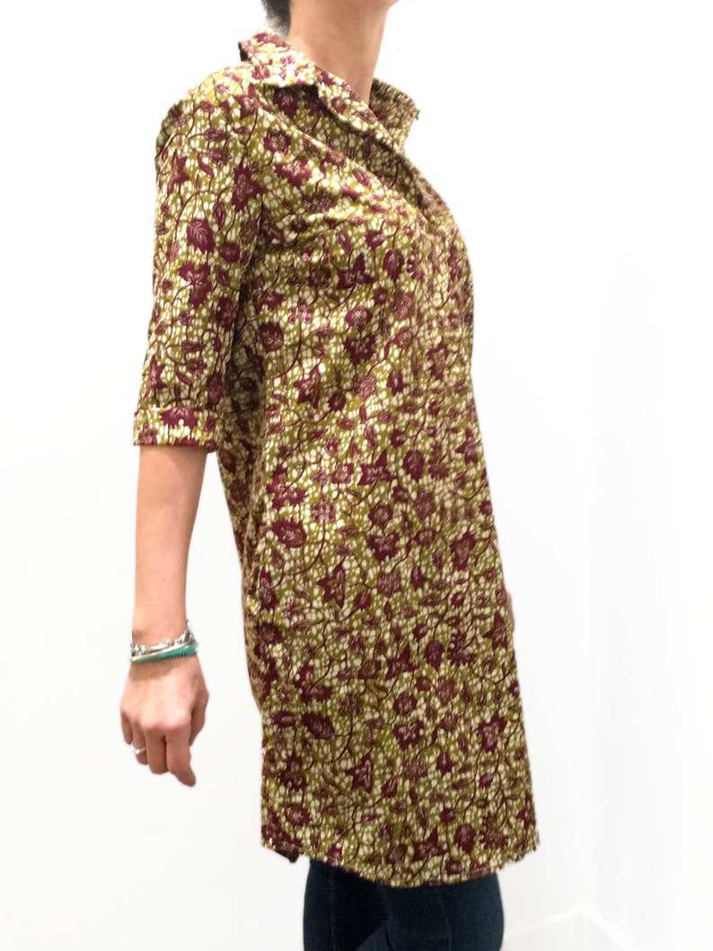 May include: A long-sleeved shirt dress with a floral print in shades of green, brown, and white. The dress has a collared neckline and a button-up front.