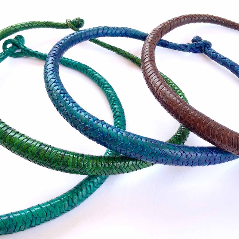 May include: Three braided leather necklaces in shades of green, blue, and brown. The necklaces are all circular and have a knot at the top.