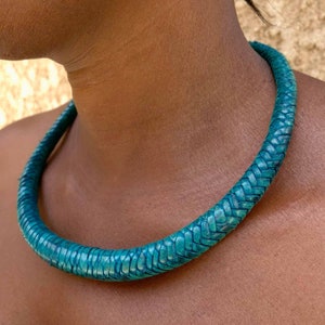 May include: A teal blue leather choker necklace. The necklace is made of braided leather and is a simple, elegant design.