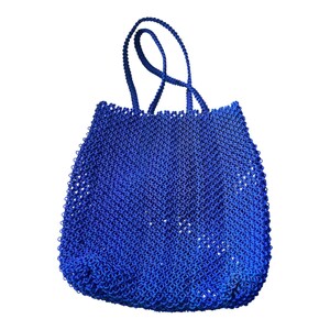Könnte beinhalten: Eine leuchtend blaue Tragetasche mit einem gewebten, offen gewebten Design. Die Tasche hat zwei stabile Griffe zum Tragen. Die Farbe der Tasche ist ein tiefes, sattes Blau, und die offene Webart verleiht ihr ein strukturiertes Aussehen.