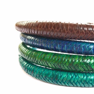 May include: Four leather bracelets in different colors, stacked on top of each other. The top bracelet is brown, the next is blue, the next is green, and the bottom bracelet is a lighter shade of green.