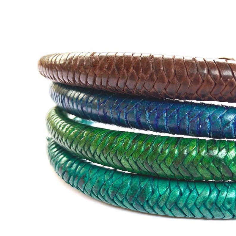 May include: Four leather bracelets in different colors, stacked on top of each other. The top bracelet is brown, the next is blue, the next is green, and the bottom bracelet is a lighter shade of green.
