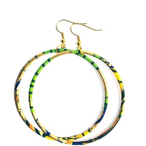 May include: A pair of large hoop earrings with a gold-tone metal base. The hoops are wrapped in fabric with a colorful pattern of green, yellow, blue, and orange. The earrings have gold-tone ear wires.