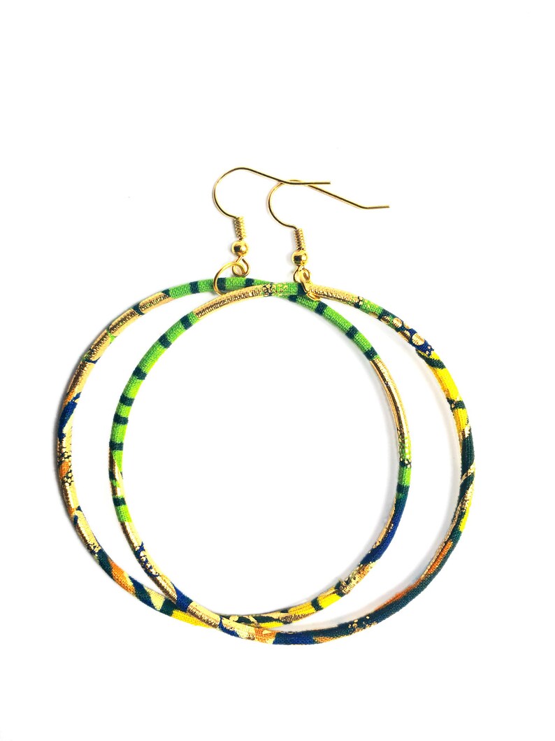 May include: A pair of large hoop earrings with a gold-tone metal base. The hoops are wrapped in fabric with a colorful pattern of green, yellow, blue, and orange. The earrings have gold-tone ear wires.