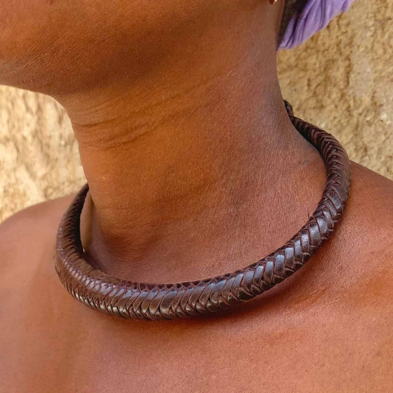 May include: A brown leather choker necklace with a braided design.