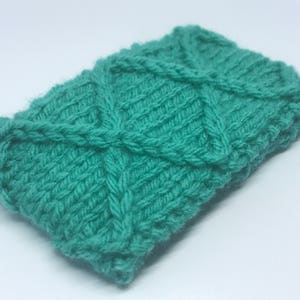 May include: A teal blue knitted headband with a diamond pattern.