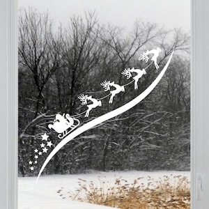 May include: White silhouette of Santa Claus in a sleigh pulled by reindeer flying through a snowy forest. The reindeer are in a line, with Santa at the front. The image is a window cling.