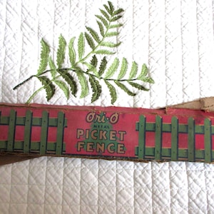 May include: A vintage Ori-O metal picket fence product box featuring a red and green graphic of a picket fence with the text Ori-O METAL PICKET FENCE, accompanied by a green embroidered fern leaf applique with detailed stitching.