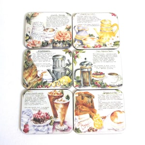 May include: A set of six square coasters featuring watercolor illustrations of coffee drinks including Caffe Mocha, Cafe au Lait, Espresso, French Press, Iced Caffe Latte, and Cappuccino. Each coaster displays a recipe and beverage imagery.