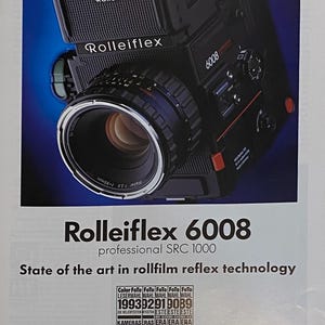 May include: A black Rollei Rolleiflex 6008 professional SRC 1000 camera with a large lens. The camera has the text "Rolleiflex" and "6008" printed on it. The image also includes the text "State of the art in rollfilm reflex technology".