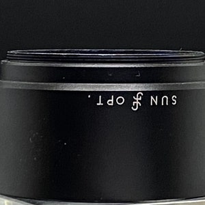 Puede incluir: Tapa de lente negra con el texto "SUN OPT." impreso en blanco.