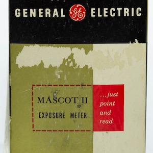 May include: A black and green box with the text "GENERAL ELECTRIC" in white letters and a red GE logo. The box also has the text "MASCOT II EXPOSURE METER" in white letters and the text "...just point and read" in red letters.