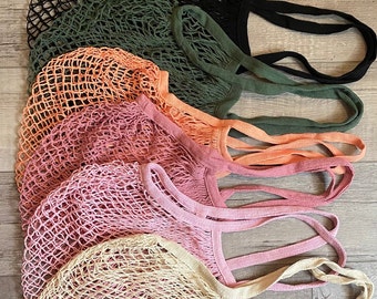 May include: Five colourful string mesh bags with handles. The bags are arranged in a stack, with the black bag on top and the natural coloured bag on the bottom. The bags are made of a soft, lightweight material and are perfect for carrying groceries or other items.
